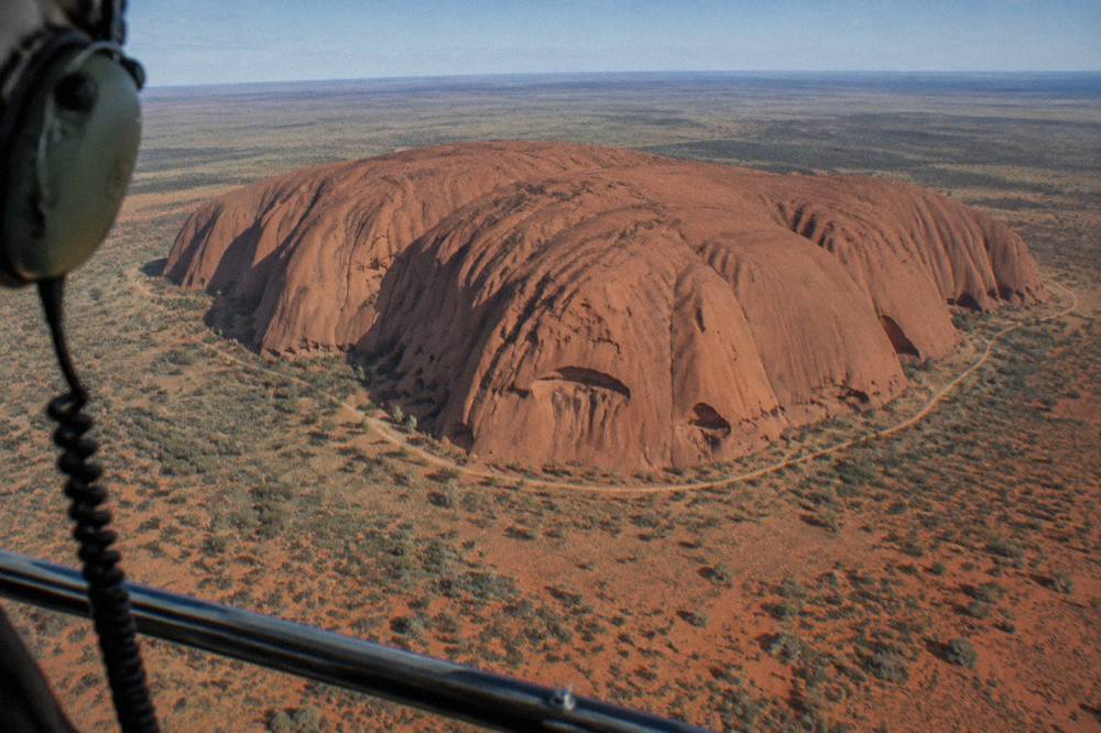 Aerial view of Uluru with a helicopter in the foreground