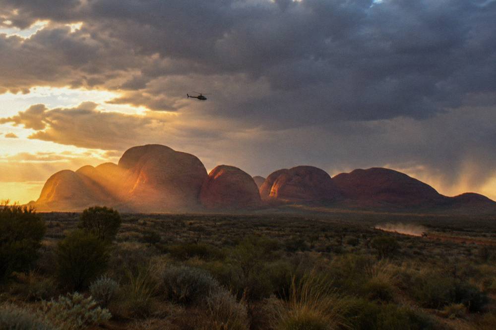 Helicopter flying over Kata Tjuta domes at sunset