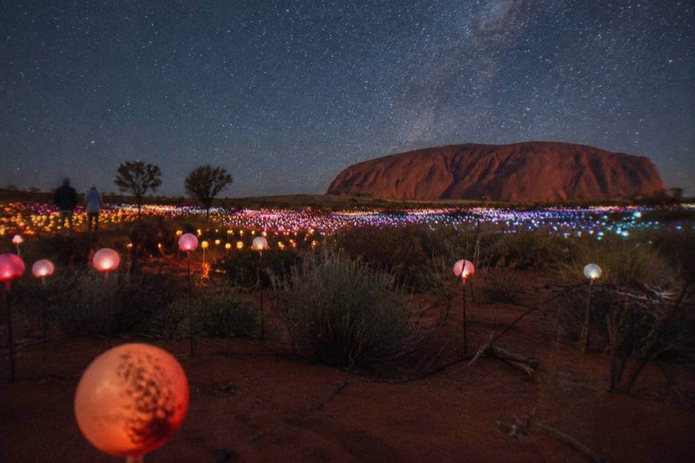 Glowing spheres in shifting colours stretching across open desert under a dark sky