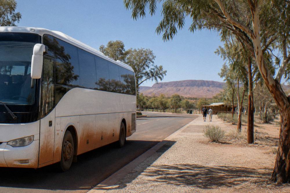 Straight sealed road through red desert landscape, blue sky, distant range