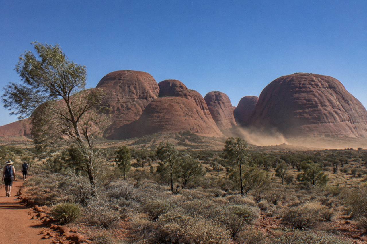 Kata Tjuta's many domes rise from the red desert plain under a clear blue sky