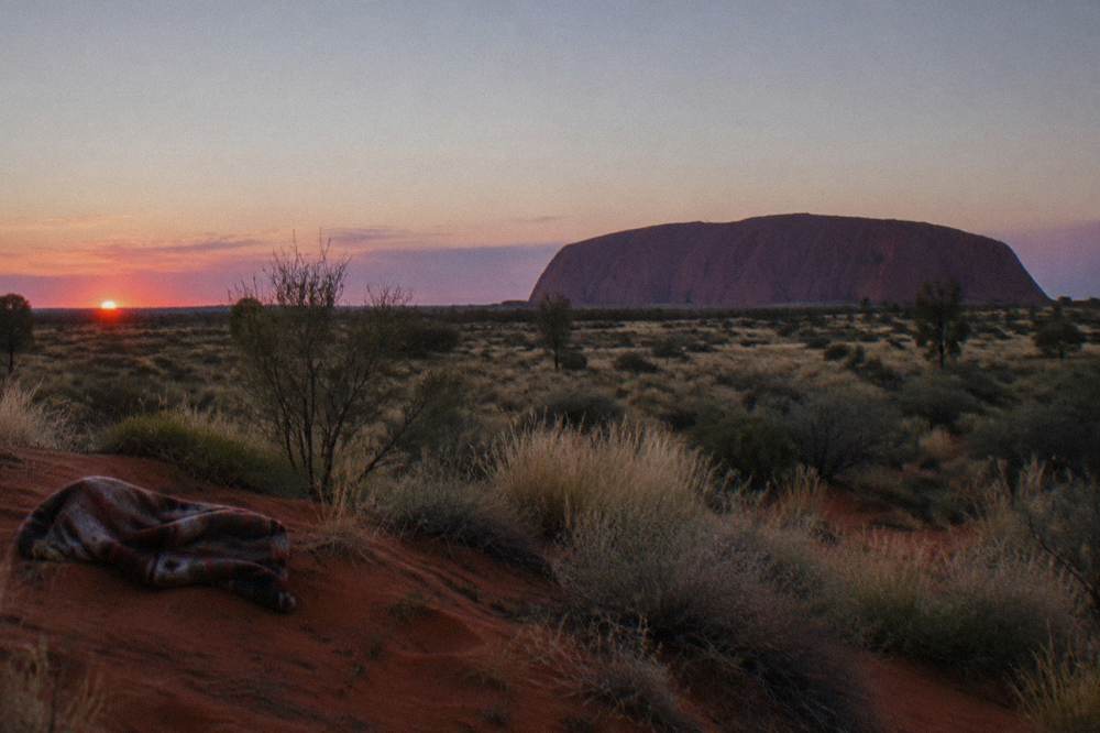 First light warming the desert plain with soft purple sky above the horizon