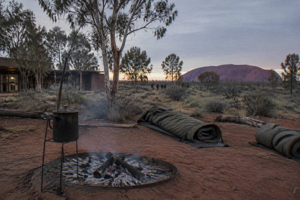 Campfire glowing at an outback campground with swags rolled out on red dirt