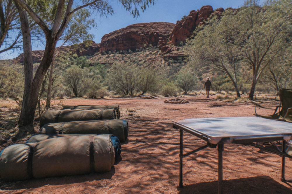 Rolled swags lined up beside a camp table under a wide open sky