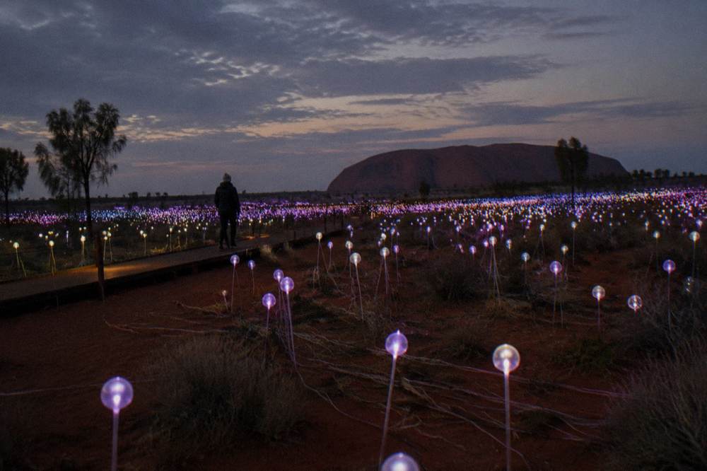 Glowing coloured light spheres scattered across dark desert sand at night