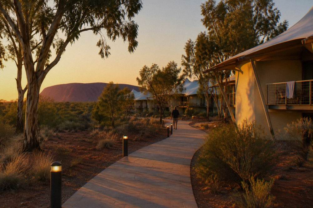 Desert hotel grounds at golden hour with gum trees and a lit path