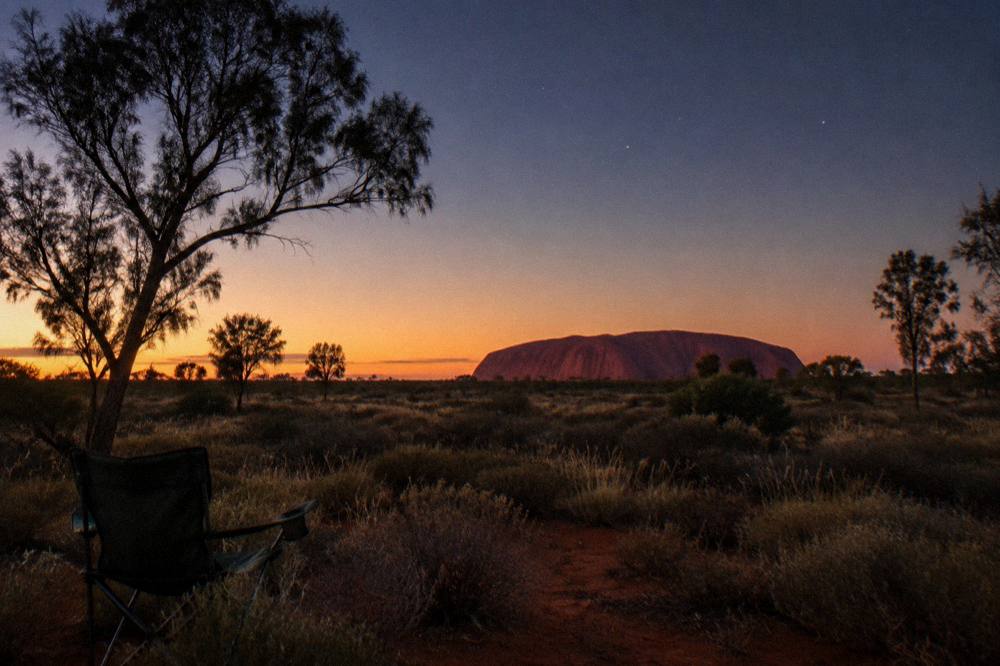 Glowing desert horizon at dusk with silhouetted scrub and open sky