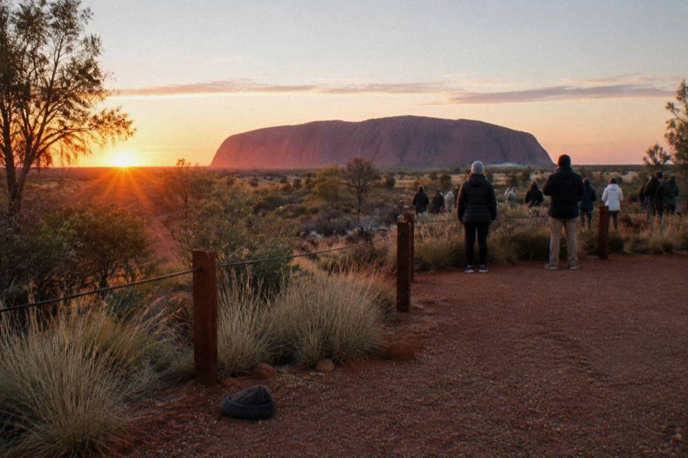 Sunrise viewing platform at Talinguru Nyakunytjaku with visitors looking toward Uluru in morning light
