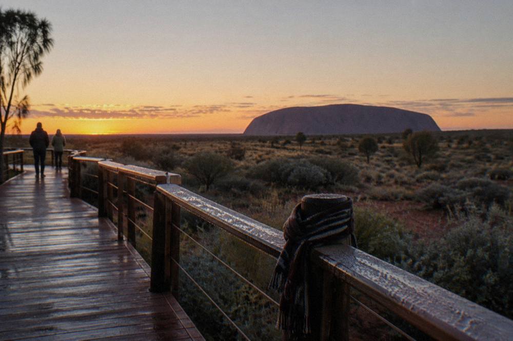 Sunrise viewing platform at Uluru with the rock silhouette on the horizon and pale dawn sky