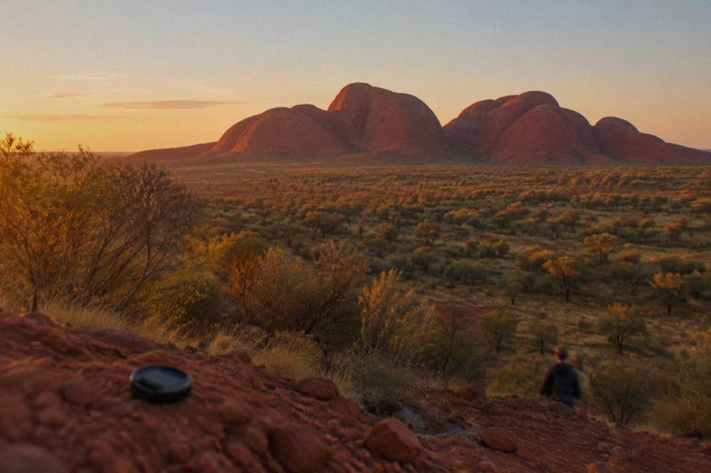 Golden evening light on a cluster of rounded red rock domes seen from a sand dune