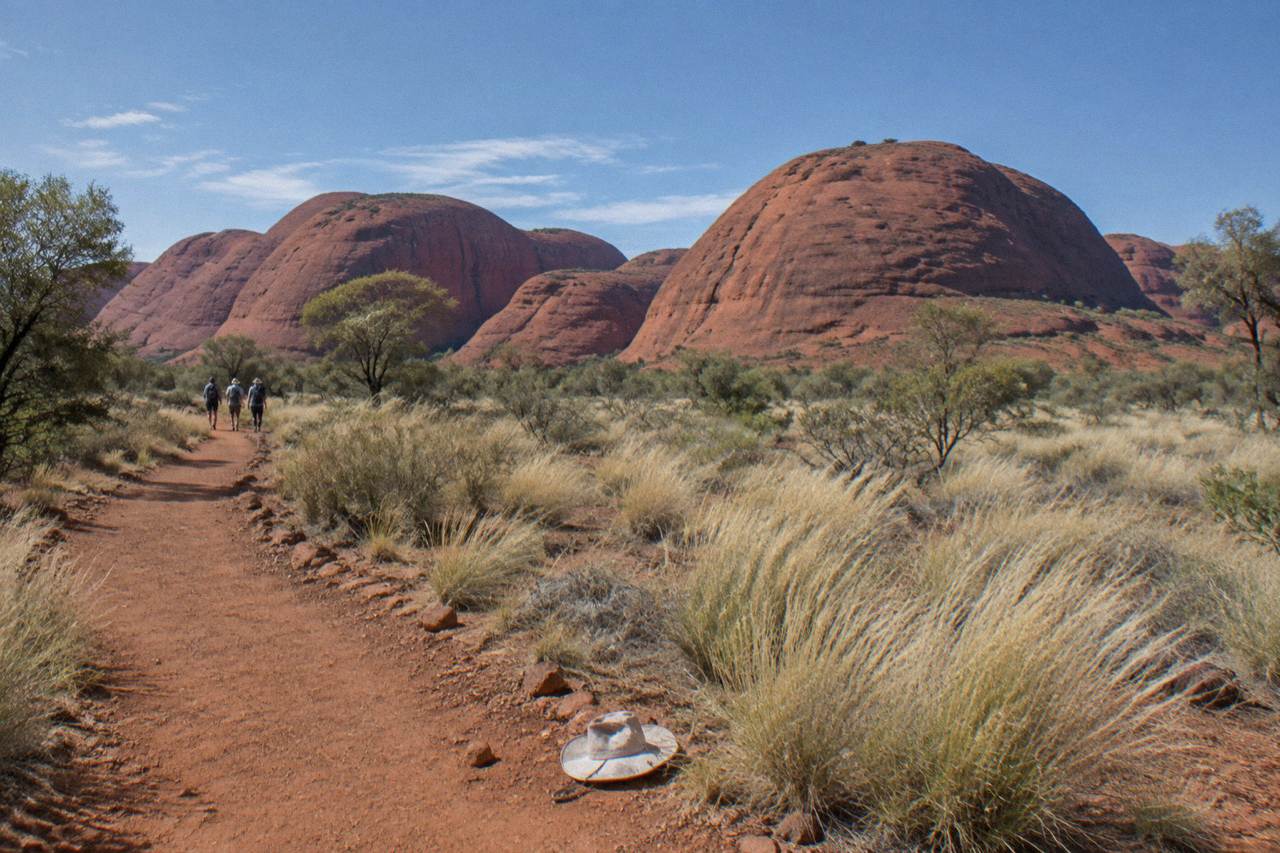 Red rock domes of Kata Tjuta rising above a desert plain under a wide blue sky